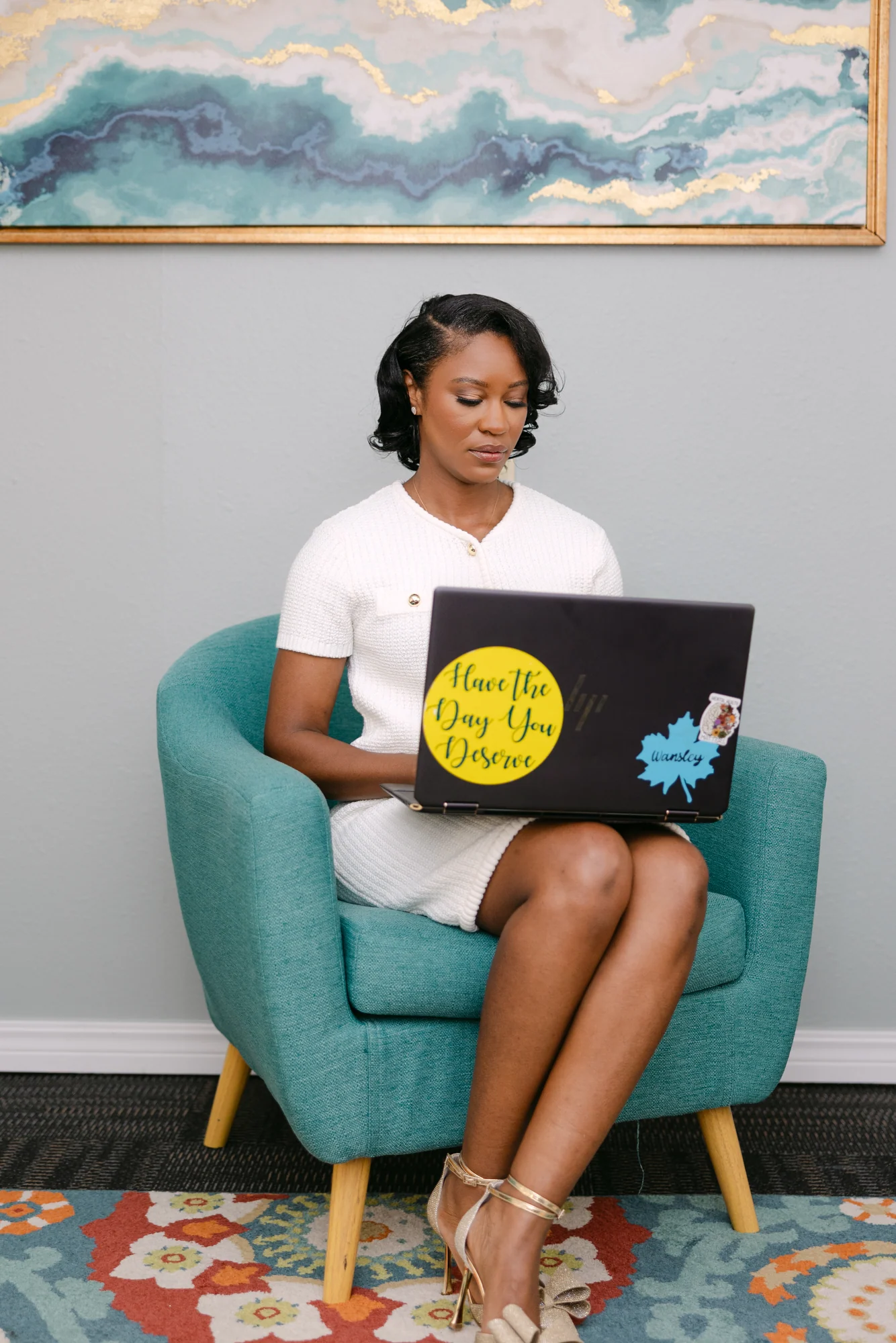 Wansley Harrison working on her laptop in a teal armchair